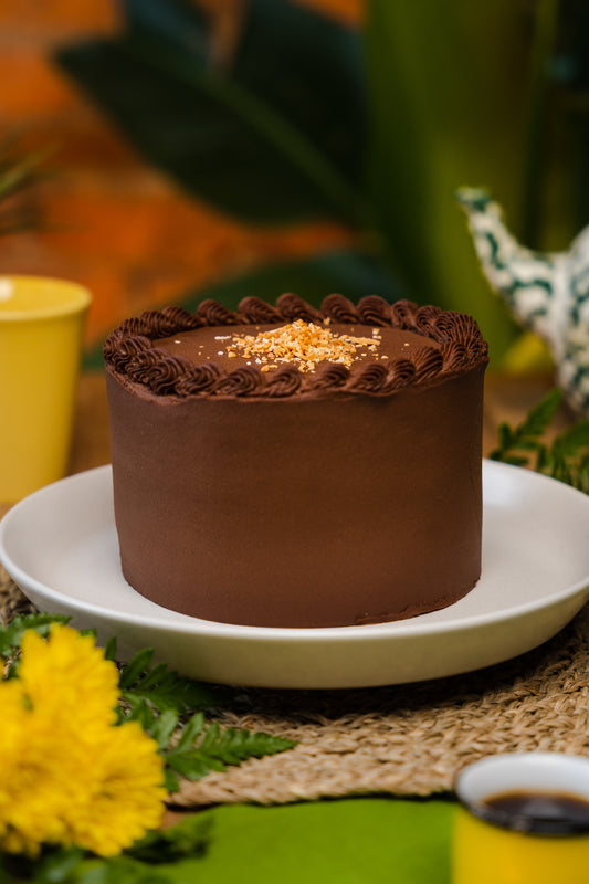 Chocolate cake filled with coconut brigadeiro topped with toasted coconut flakes, plated in a white dish. flowers decorating as so mugs