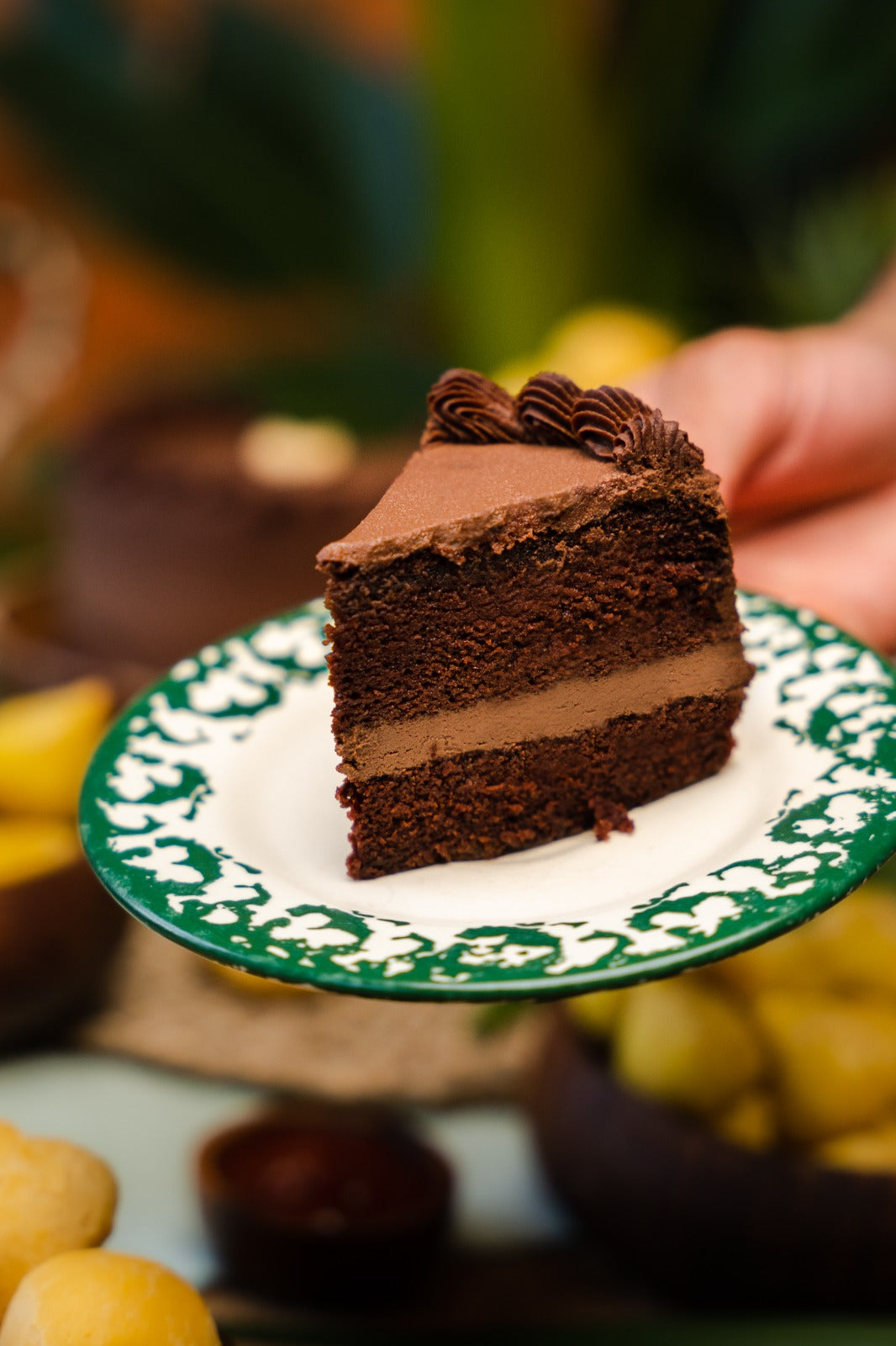 Sliced chocolate mousse cake in a white plate with green ornament around the plate