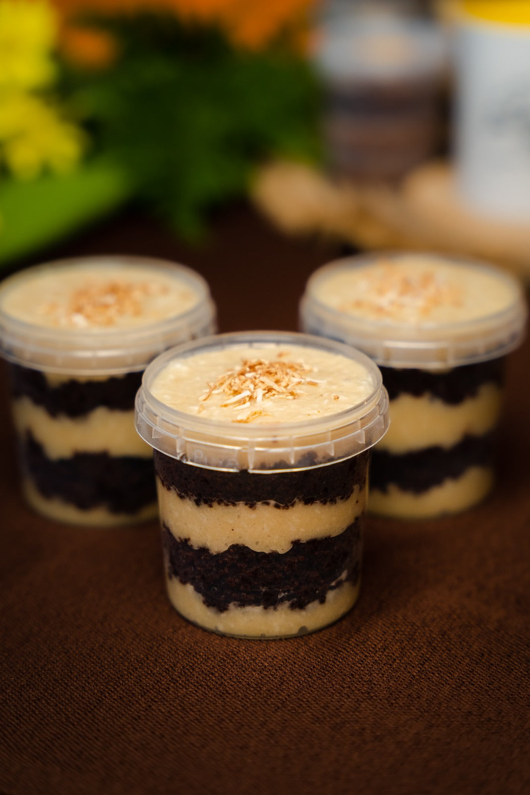 chocolate jar cake layered with coconut brigadeiro (beijinho), topped with toasted coconut flakes sitting on a brown mat